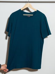 A navy blue men's t-shirt hanging on a hanger against a white wall.